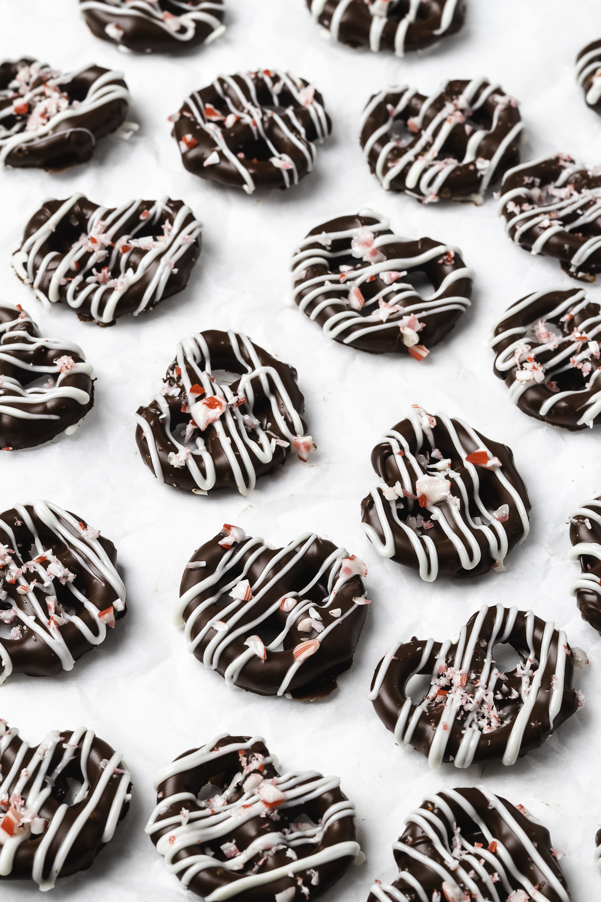 Chocolate-covered mini pretzels decorated with white chocolate drizzle and crushed peppermint candy.