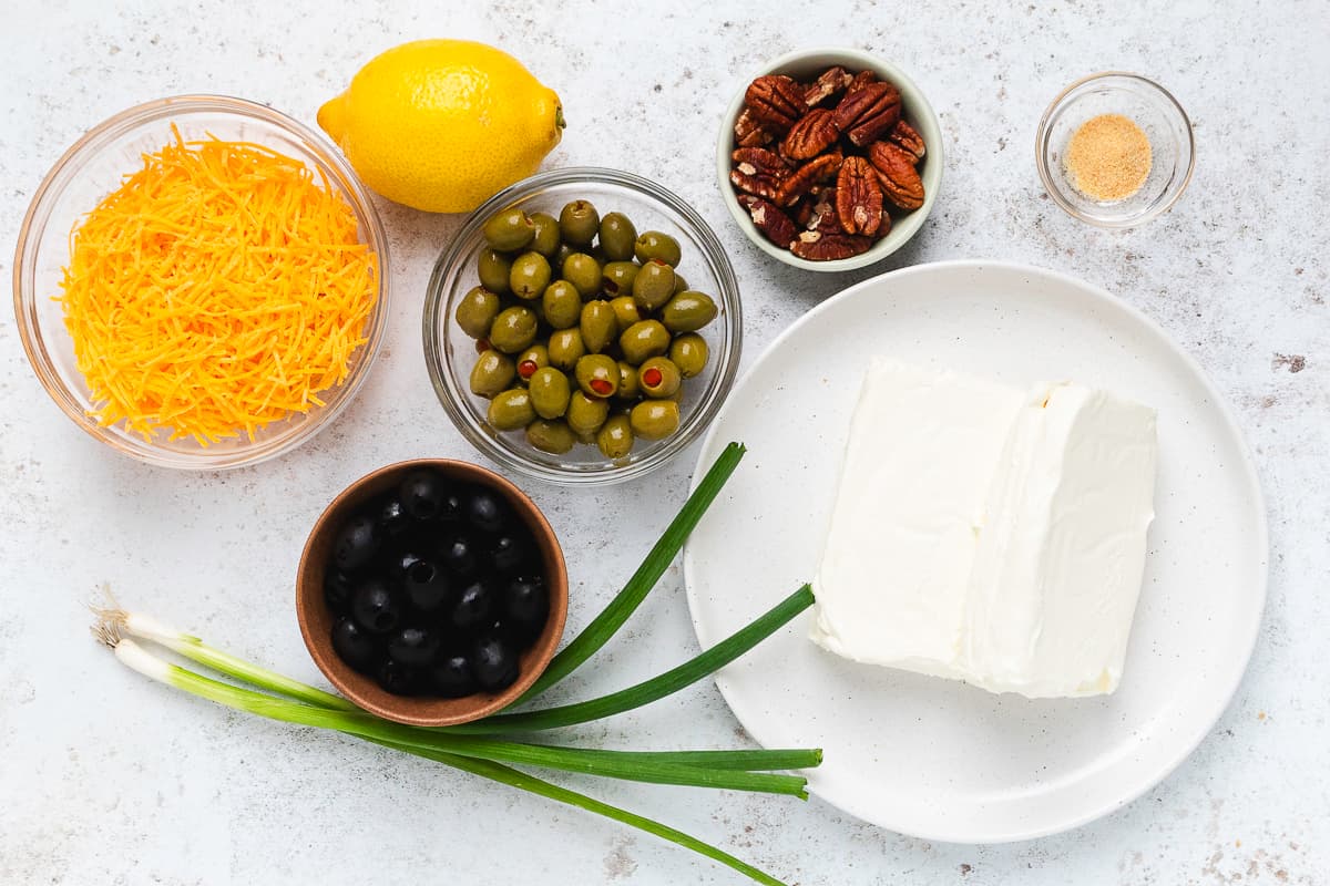 Cream cheese, olives, shredded cheddar, pecans, green onions, lemon, and seasonings for an olive cheese ball.