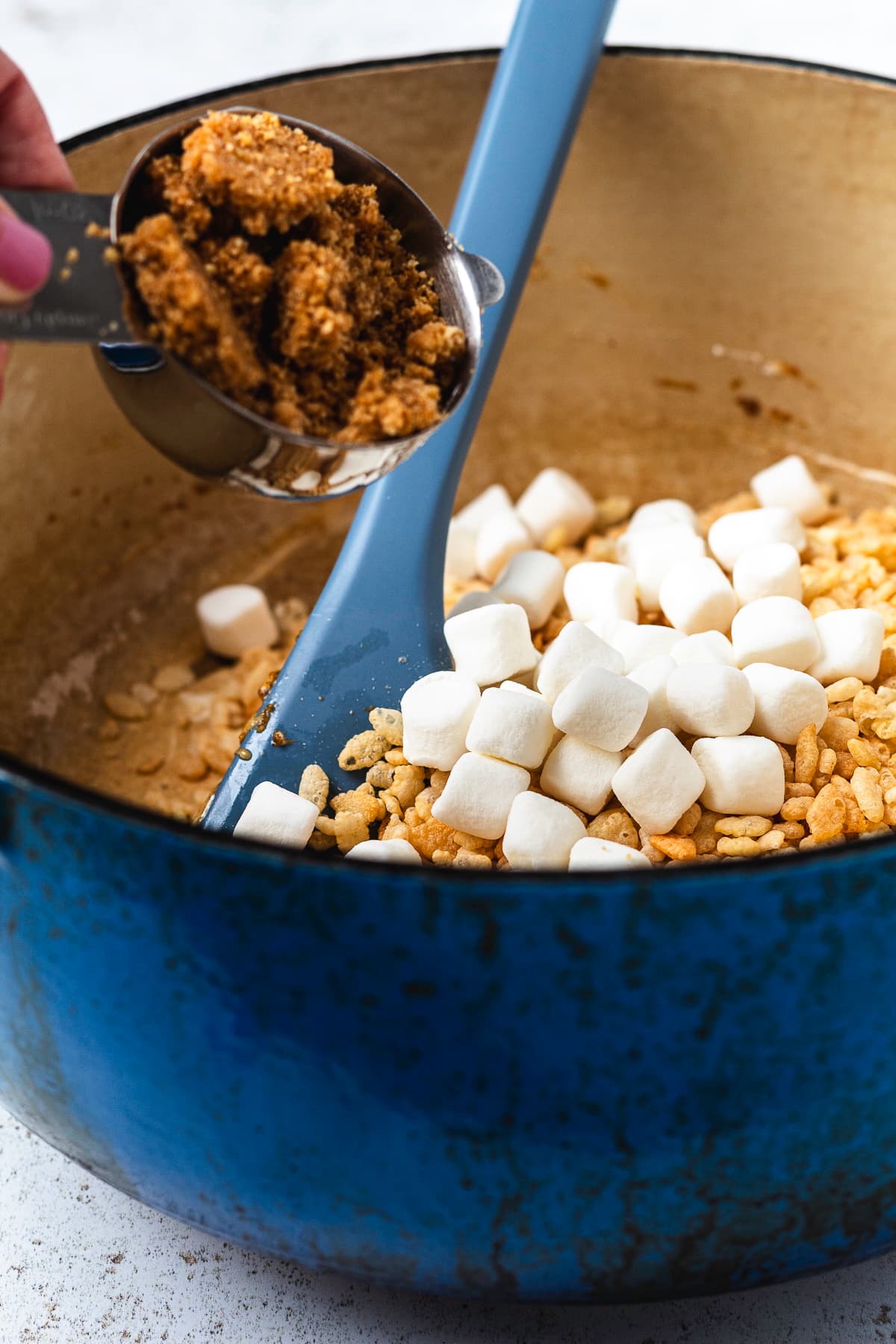 Graham cracker crumble being added to the Pumpkin Rice Krispie Treat mixture.