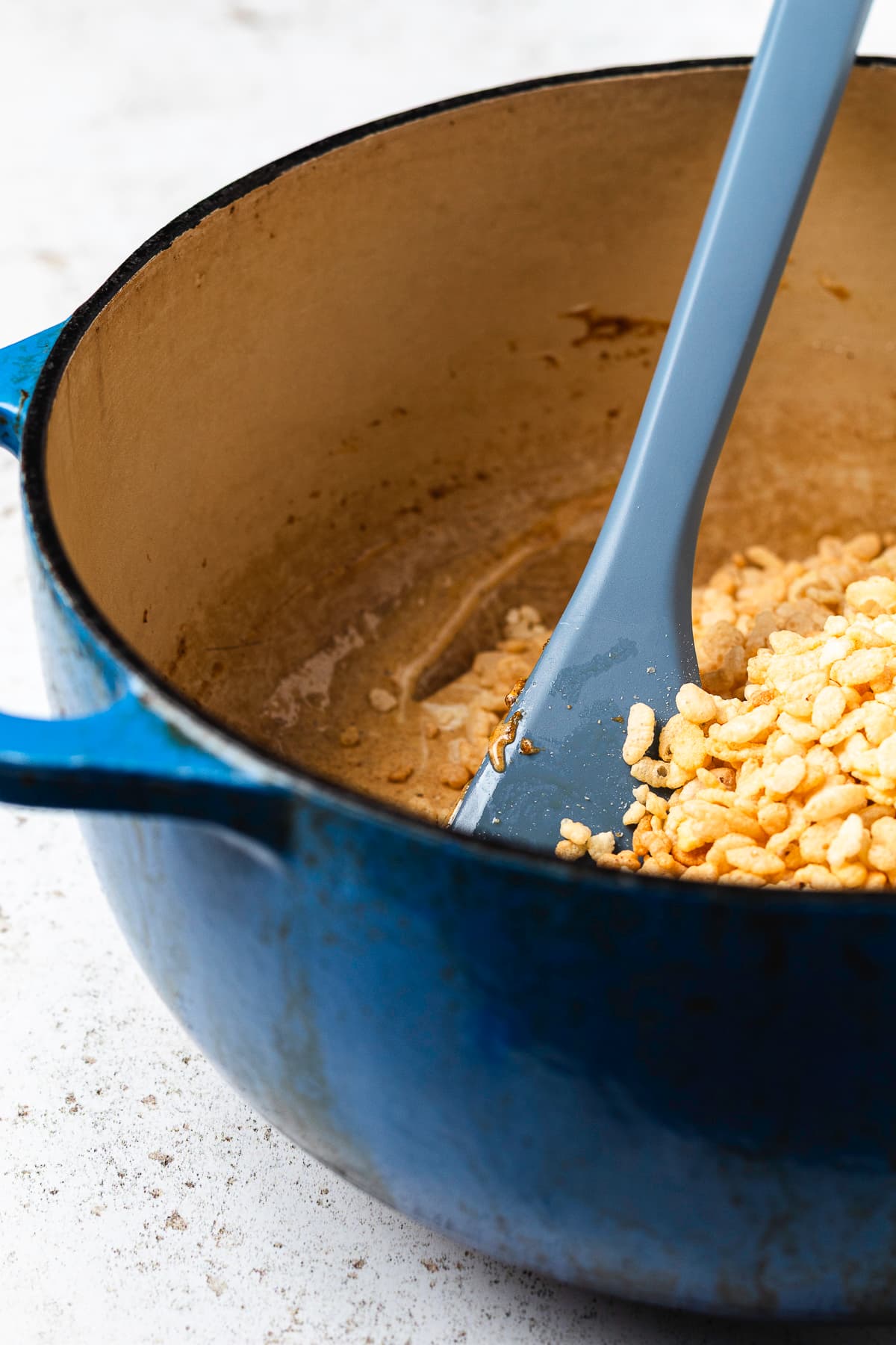 Rice Krispie cereal and mini marshmallows being added to the pumpkin mixture.