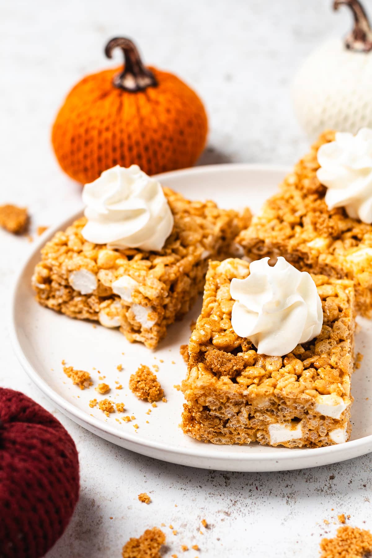 Pumpkin Rice Krispie Treats topped with whipped cream and graham cracker crumbs.