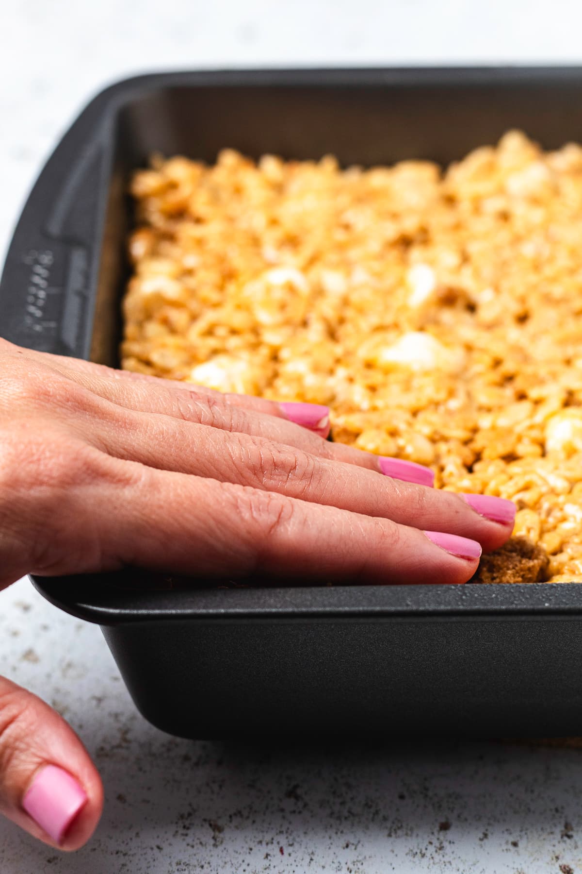 Pumpkin Rice Krispie Treat mixture being pressed into a baking pan.