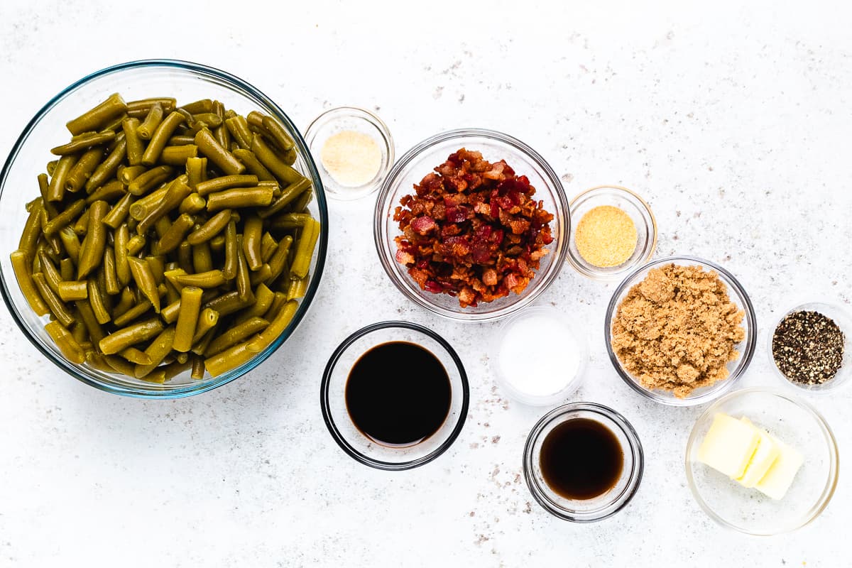 Overhead view of the ingredients for slow cooker crack green beans, including bacon, brown sugar, butter, and seasonings.
