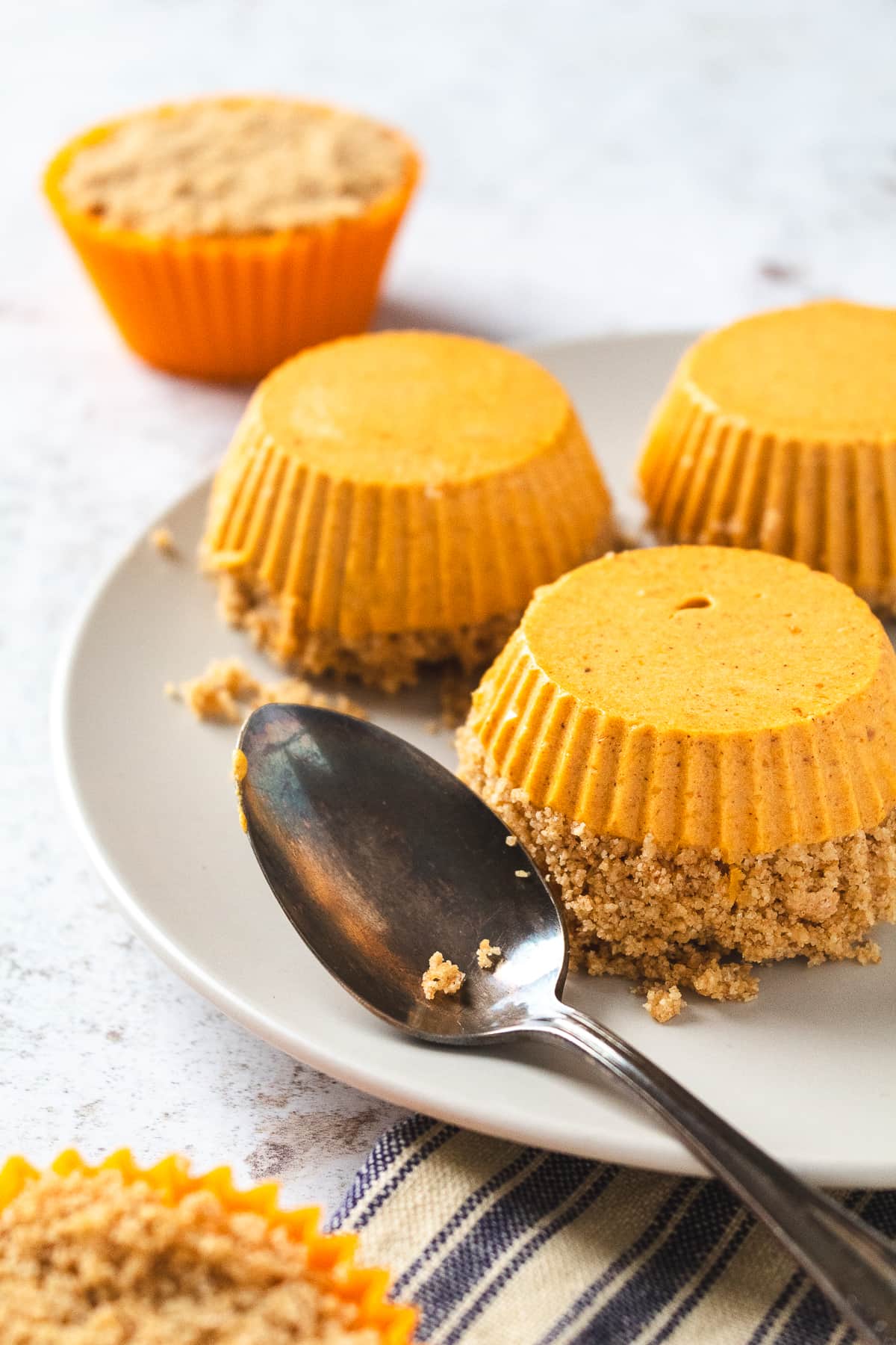Mini pumpkin cheesecake bites removed from the liners and arranged on a plate with graham cracker crust.